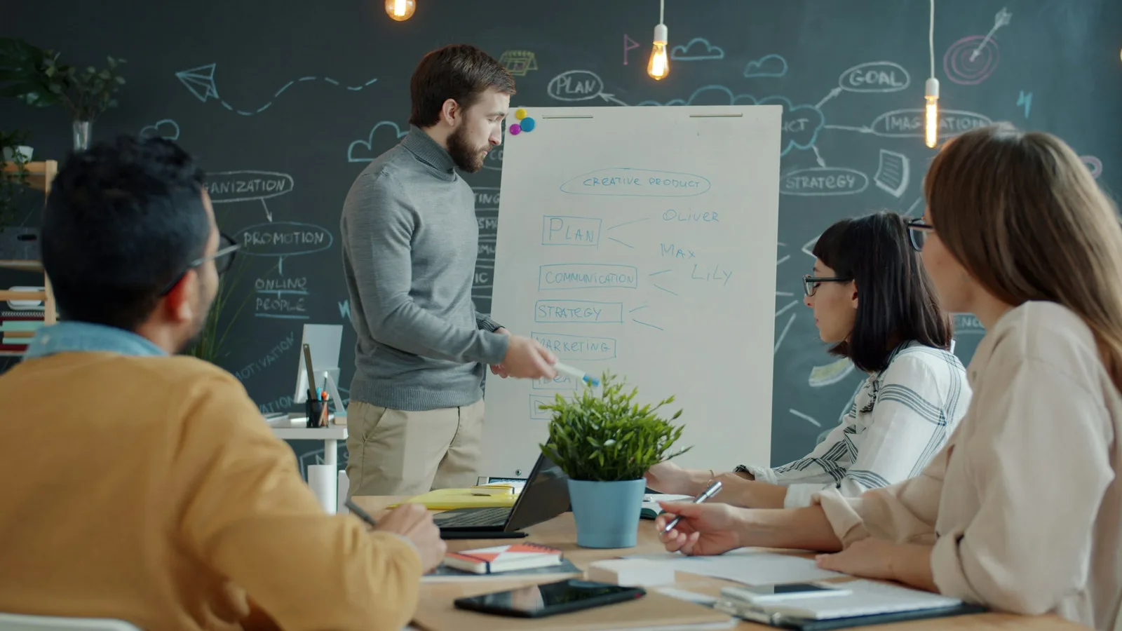 A team working through a plan together at a whiteboard in a modern office.